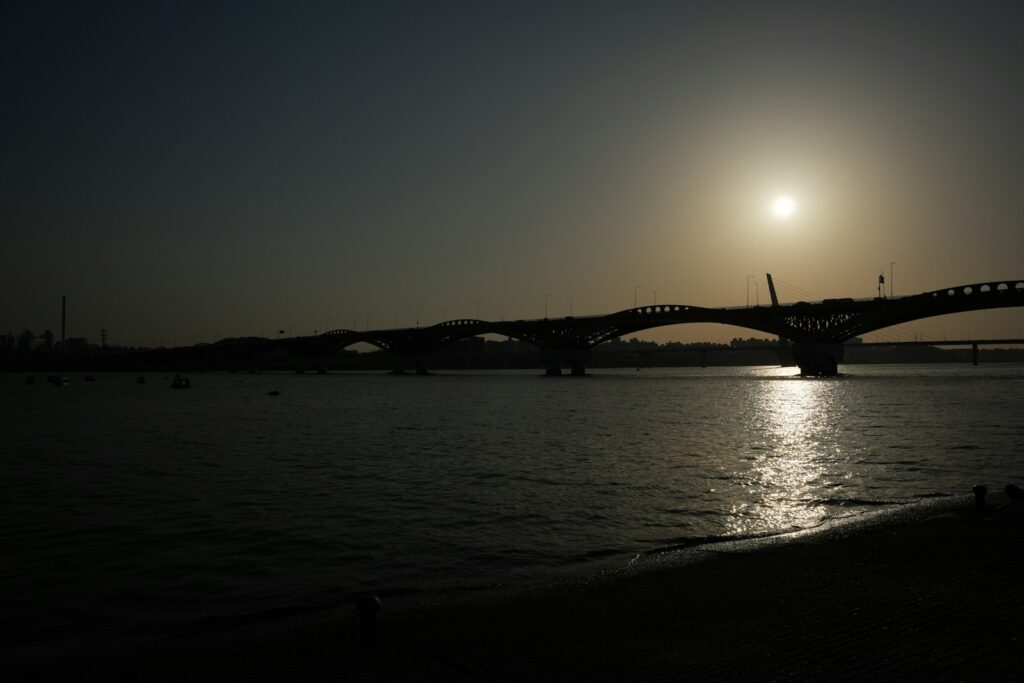 A bridge stretches across the water at sunset.